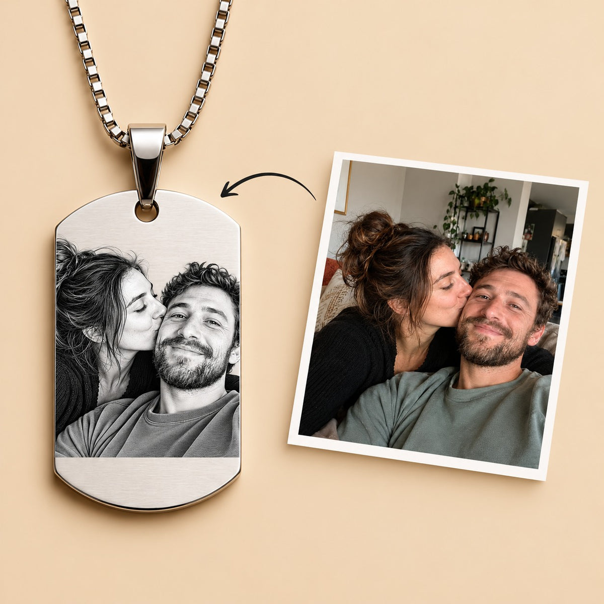 A silver dog tag necklace with a custom photo print of a couple, displayed next to a reference photo of the couple on a warm beige background.