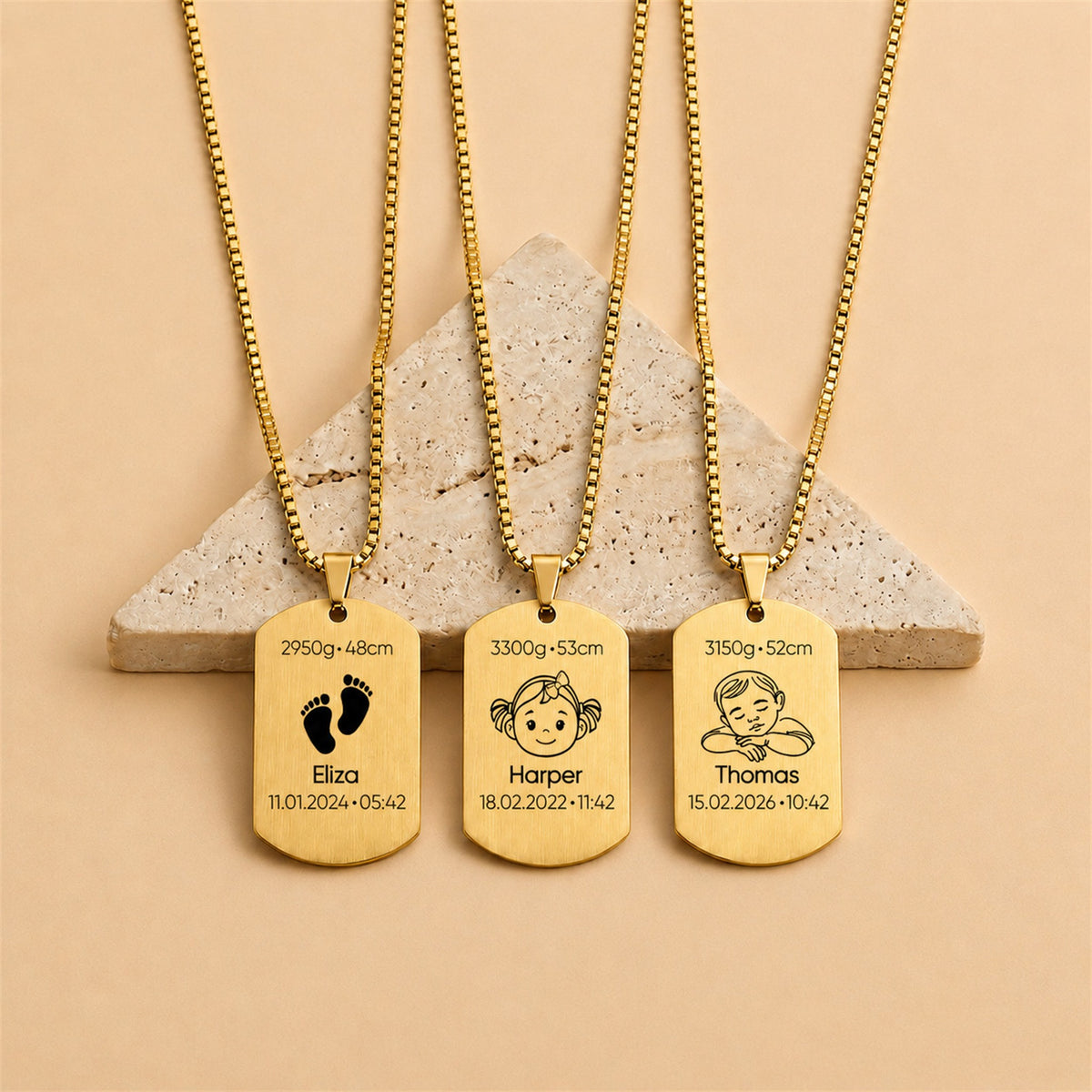 Three gold necklaces with engraved tags on a beige background